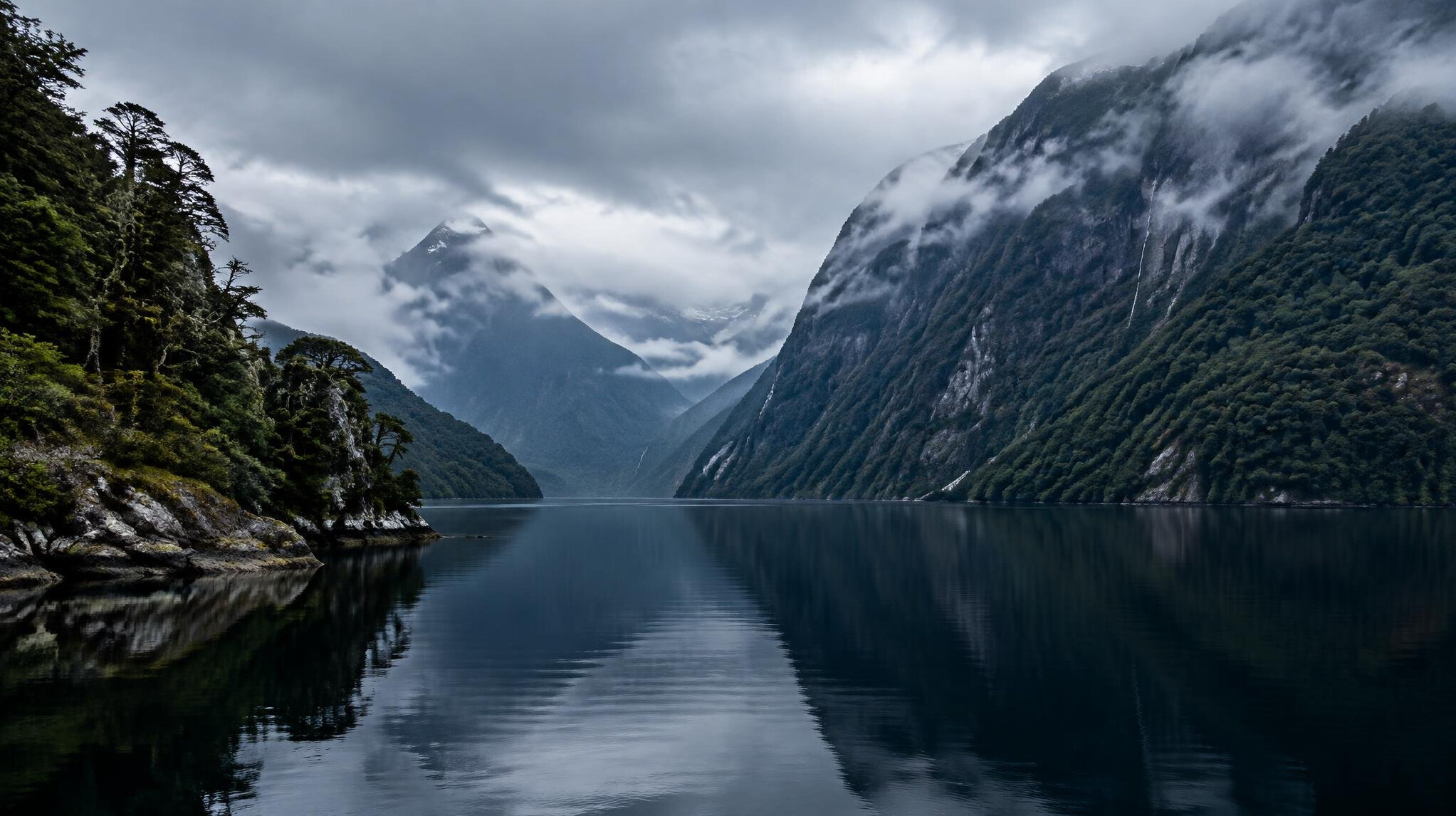 Patagonian fjord in Aysén, Chile, with low clouds and dark water